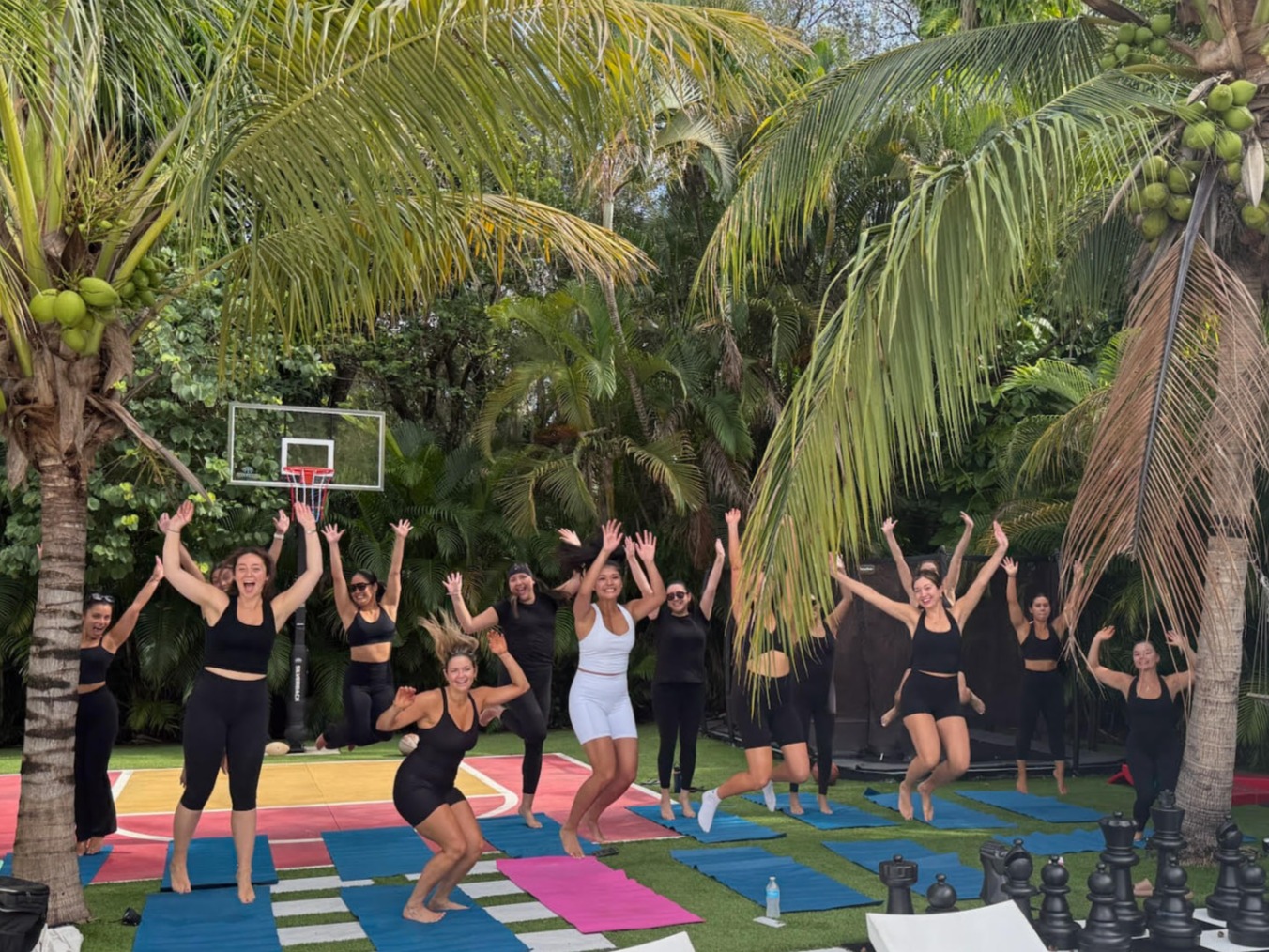 Bachelorette crew jumping mid-air after a backyard yoga class under palm trees